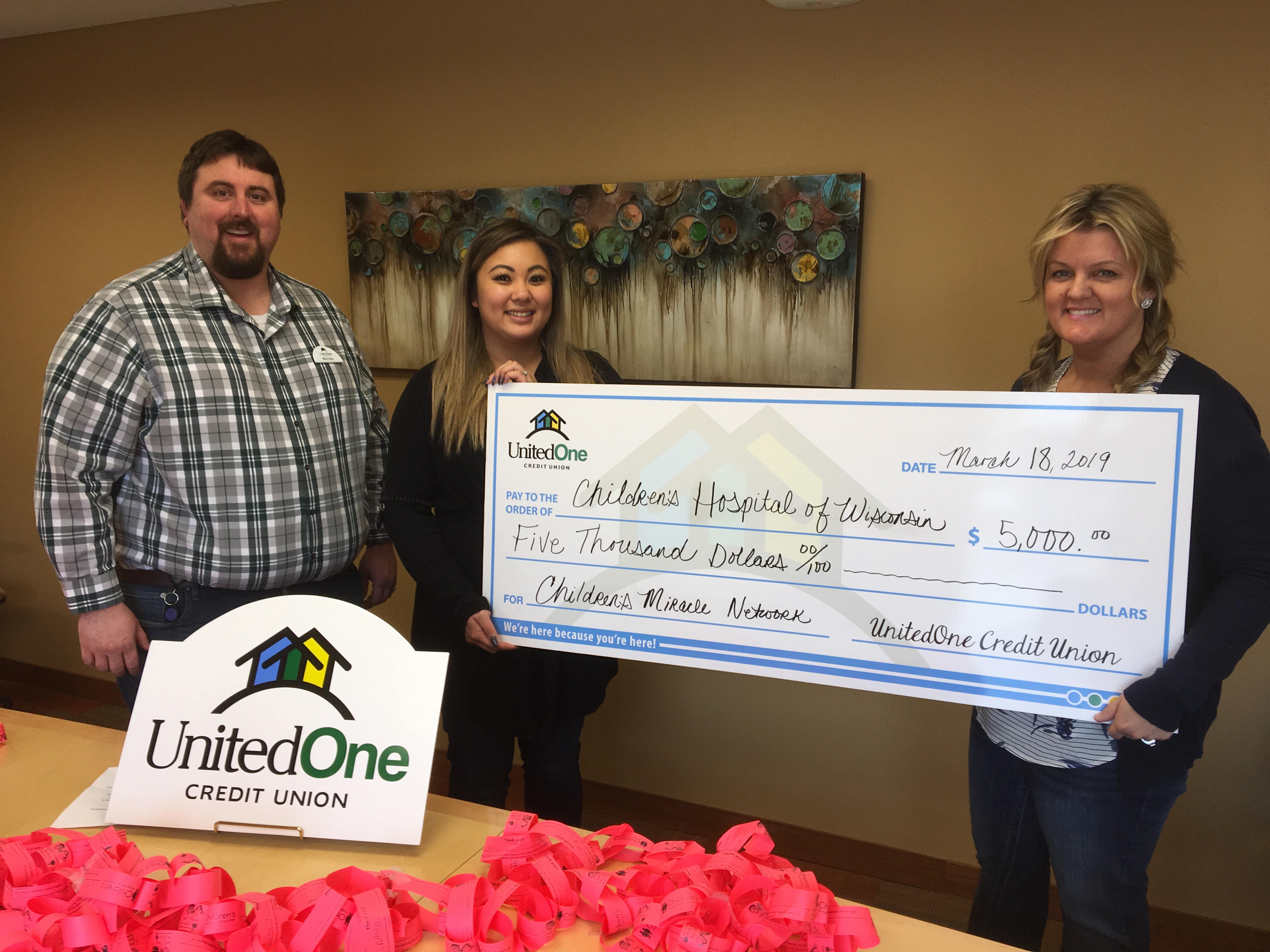 UnitedOne Credit Union employees hold a "big check" to show the donation the credit union is making to Children's Hospital of Wisconsin.